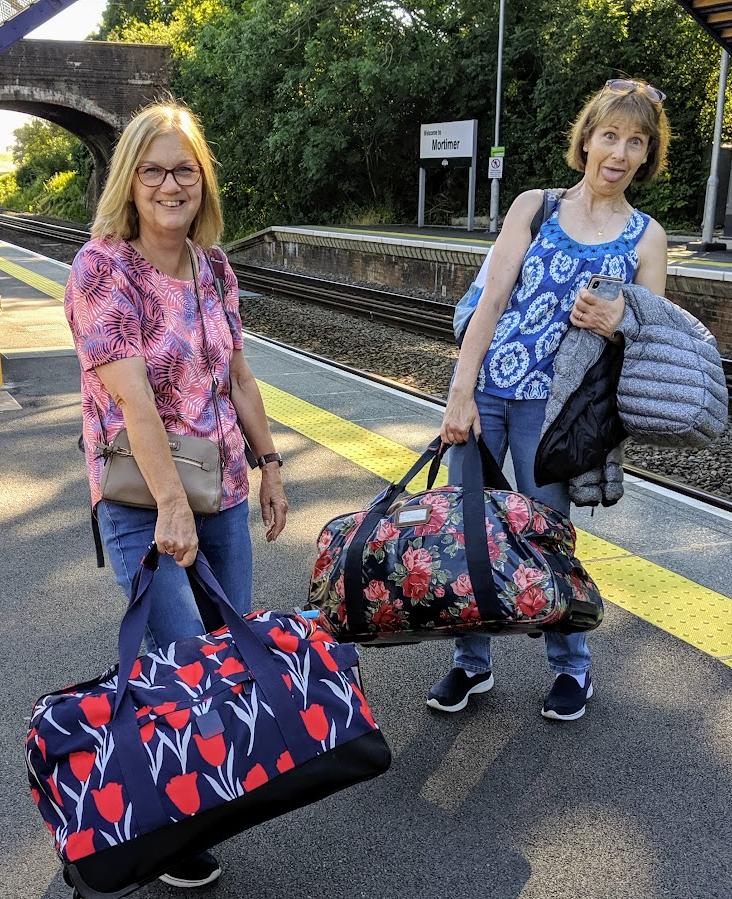 Nicky and her friend Michele on Mortimer station platform, each carrying a brightly patterned holdall, setting off on a walk
